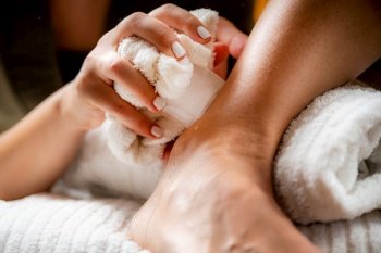 Ankle joint cryotherapy ice massage. Hands of a therapist placing ice directly onto a painful ankle to relieve pain, reduce inflammation and swelling and promote healing.. Ankle Joint Cryotherapy Ice Massage.