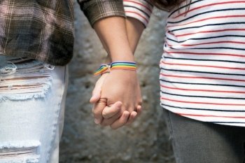 Close up of happy lesbian couple holding hands wearing rainbow flag wristband, LGBT love concept. High quality FullHD footage. Close up of happy lesbian couple holding hands wearing rainbow flag wristband, LGBT love concept.