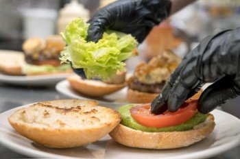 Chef cooking burger, close-up, making sandwich, fast food concept, recipe of preparing homemade hamburger with vegetables. High quality photography.. Chef cooking burger,close-up, making sandwich, fast food concept, recipe of preparing homemade hamburger with vegetables.