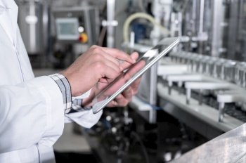 Factory worker inspecting production line on beverage factory with computer tablet. High quality photo. Factory worker inspecting production line on beverage factory with computer tablet. 