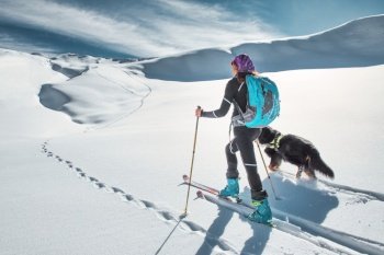 A woman ski mountaineer with her beloved dog alone in snow flats