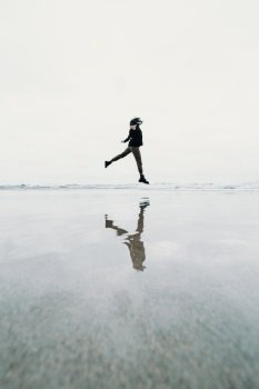 Young woman jumping jumping on the beach with a reflection over the water with copy space liberty concept