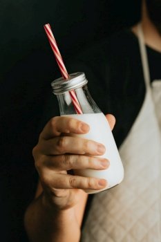 Waiter holding a milkshake close up of the bottle with copy space and moody tones