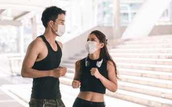 Asian sportive man and woman wearing face mask to protect virus and doing exercise by running or jogging outdoor in the morning. Health and Sport Concept.