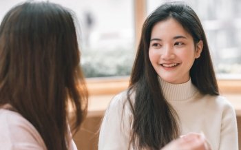 Portrait of Asian cute woman smiling and talking to her friend in coffee shop. Lifestyle Concept.