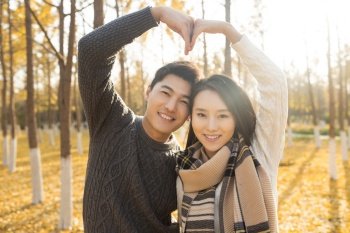 Happy young lovers making heart gesture