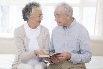 Old couple reading together at home