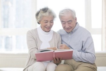 Happy old couple looking at photo album together
