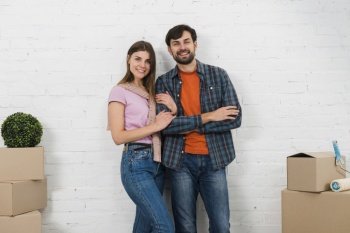 portrait smiling young couple standing front white wall looking camera