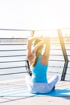 rear view young fitness woman stretching her hand sitting bridge morning sunlight