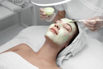 beautician applying face mask female client