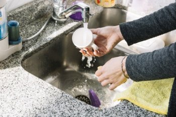close up woman s hand washing cup kitchen sink