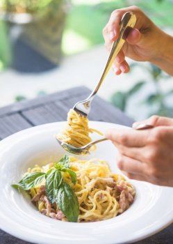 close up person holding appetizing spaghetti rolled fork spoon