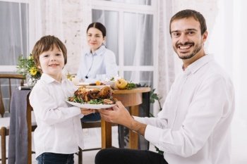 happy man with son holding chicken plate