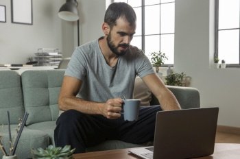 man having coffee working from home laptop