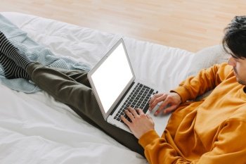 man with laptop lying bed
