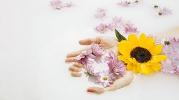 close up woman s hand with beautiful yellow pink flowers bath water