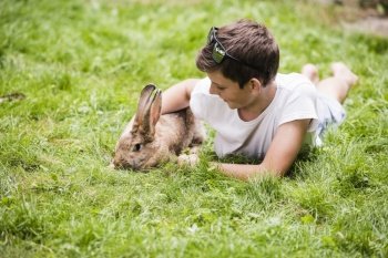 boy lying with his pet rabbit green grass