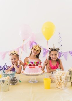pretty birthday girl with her friends wearing eye mask standing variety food table