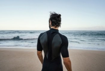 surfer walking alongside ocean from shot