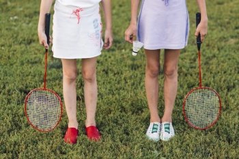 low section girl standing green grass holding badminton shuttlecock