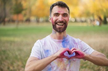 smiling man showing love sign with painted hands
