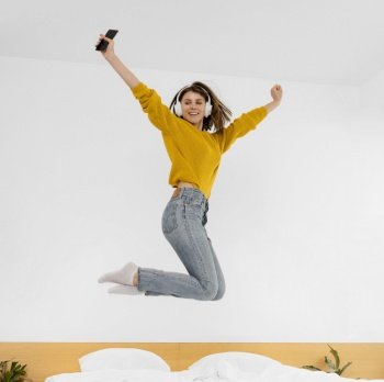 full shot woman jumping bed