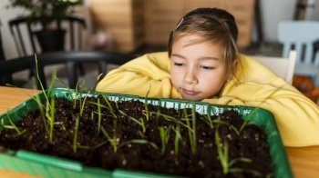front view girl watching sprouts grow home