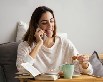 woman talking phone while having breakfast home