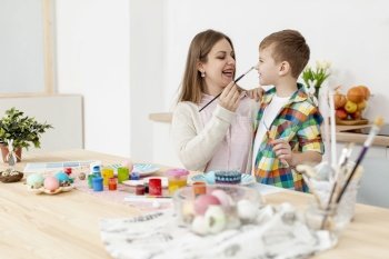 mother son having fun while painting eggs