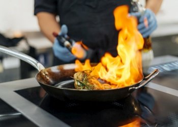 chef with gloves flambeing dish