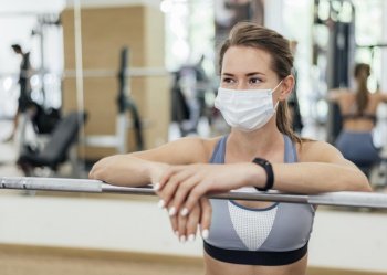 woman training gym during pandemic with mask