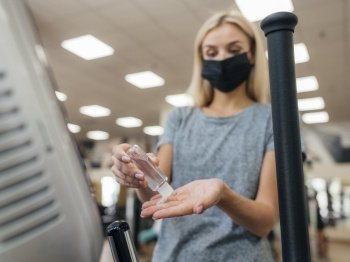 woman using hand sanitizer gym during pandemic
