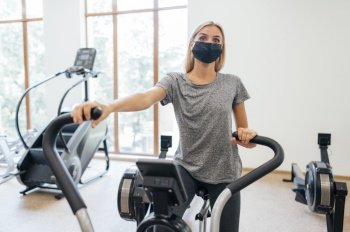 woman with medical mask during pandemic exercising gym