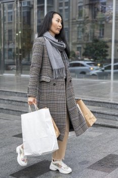 full shot woman carrying shopping bags