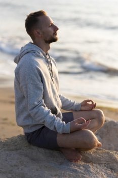 side view man meditating beach