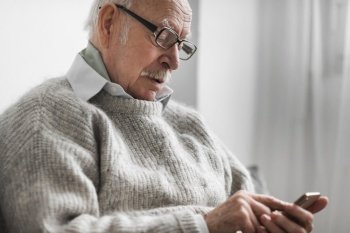 side view old man nursing home using smartphone