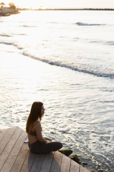 side view woman meditating sea