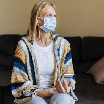 woman home during quarantine with medical mask smartphone