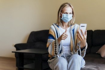 woman home during self isolation with medical mask smartphone