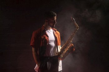 male musician spotlight holding saxophone