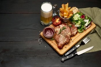 Grilled roated beef steaks, potato and sauce on wooden cutting board.. Grilled roated beef steaks, potato and sauce on wooden cutting board