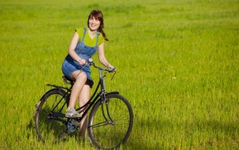 Happy woman  with a bicycle in a green meadow