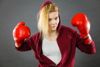 Sporty woman wearing red boxing gloves, fighting. Studio shot on dark background.. Woman wearing boxing gloves