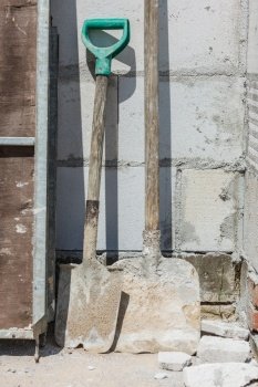 Shovel covered in dust and concrete standing on industrial construction site.. Shovel on construction site
