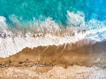 Top down view. Sea waves and sand beach shore. Summertime.. Aerial view. Sea waves and sandy beach