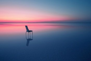 Chair among smooth water of lake at the sunset. The concept of solitude and unity with nature. A chair stands in the water of the Salt Lake Ace. Anatolia, Turkey. Chair among smooth water of lake at the sunset