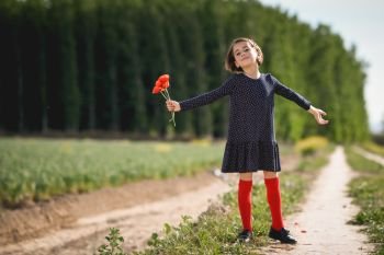 Little girl walking in nature field wearing beautiful dress with flowers in her hand.. Little girl walking in nature field wearing beautiful dress