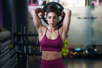 Athletic woman doing triceps push-ups with a barbell plate at the gym.. Athletic woman doing triceps push-ups with a barbell plate