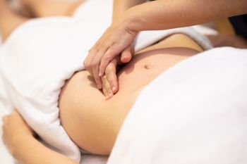 Woman receiving a belly massage at spa salon. Female patient is receiving treatment by professional osteopathy therapist.. Woman receiving a belly massage at spa salon